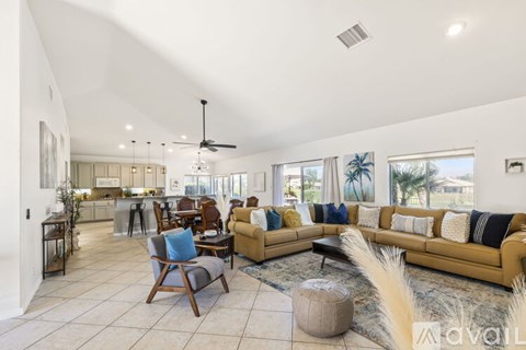 A spacious living room with a yellow sofa and a wooden chair.
