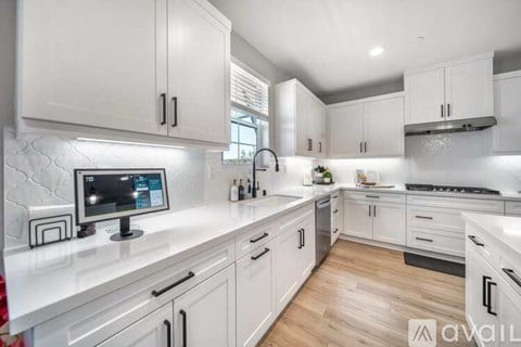 A modern kitchen with white cabinets and a central island with a computer on it.