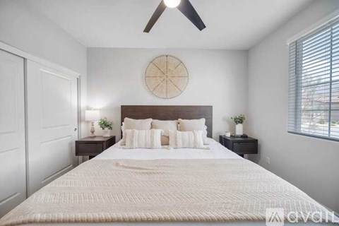 A bedroom with a large bed and a ceiling fan.