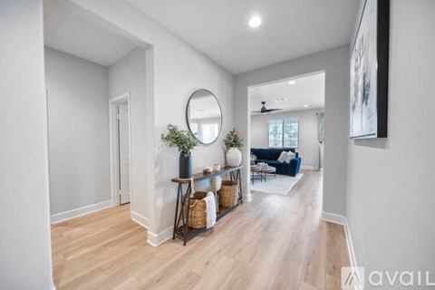 A spacious living room with a couch, a table with a plant, and a mirror on the wall.