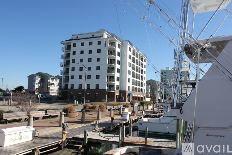 A white boat is docked at a pier in front of a white building.