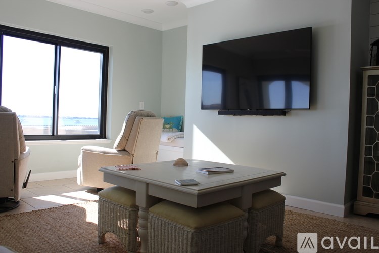 A living room with a flat screen TV mounted on the wall and a chair with a table in front of it.