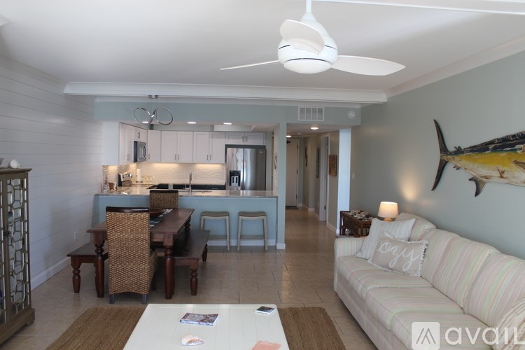 A living room with a white couch and a dining table with chairs.