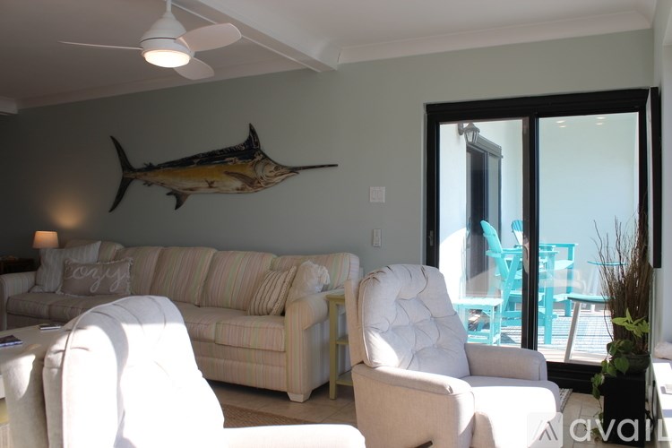 A living room with a white chair and a fish picture on the wall.