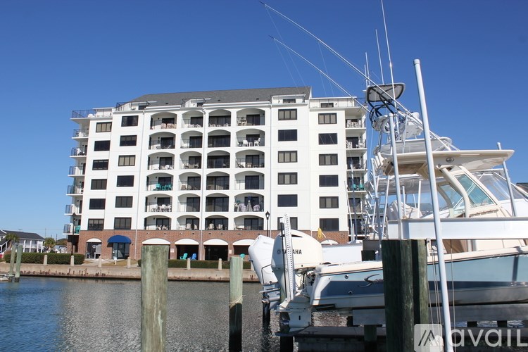 A white boat is docked in front of a white building with a blue awning.