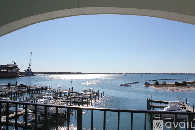 A view from a balcony overlooking a marina with boats and a crane in the distance.