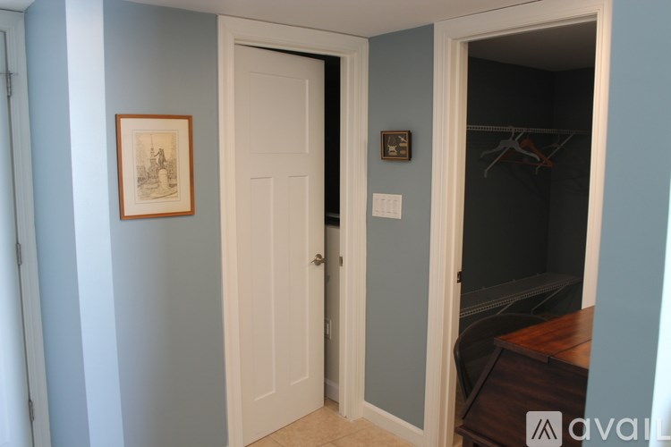 A room with a white door and a picture on the wall.