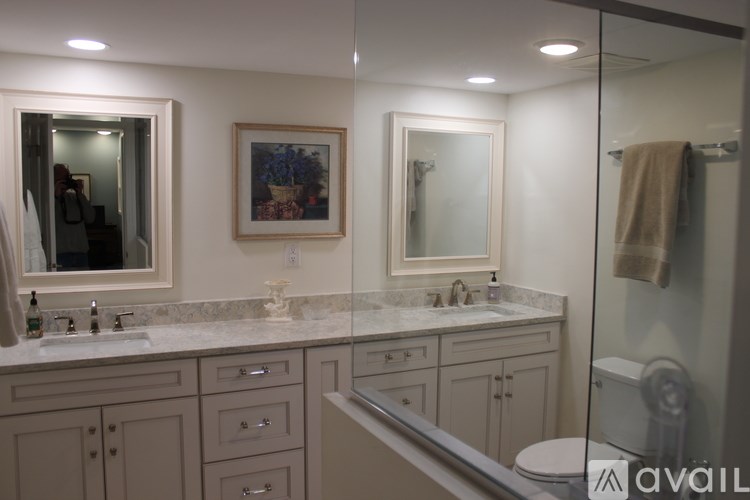 A bathroom with a large mirror, a sink, and a towel hanging on the door.