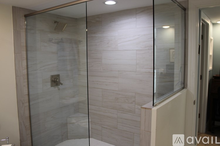 A bathroom with a glass shower door and a marble wall.