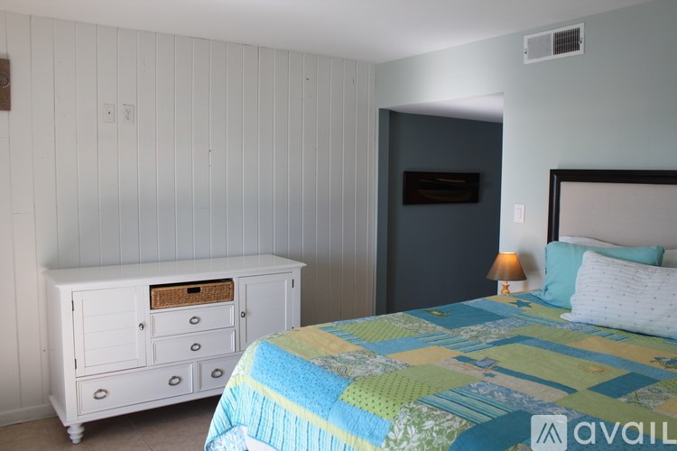 A bedroom with a bed, nightstand, and a dresser.