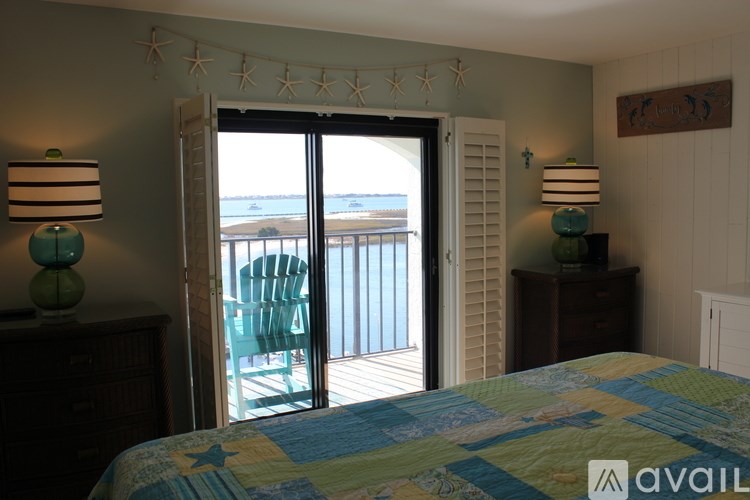 A bedroom with a bed, two lamps, and a view of the outside.