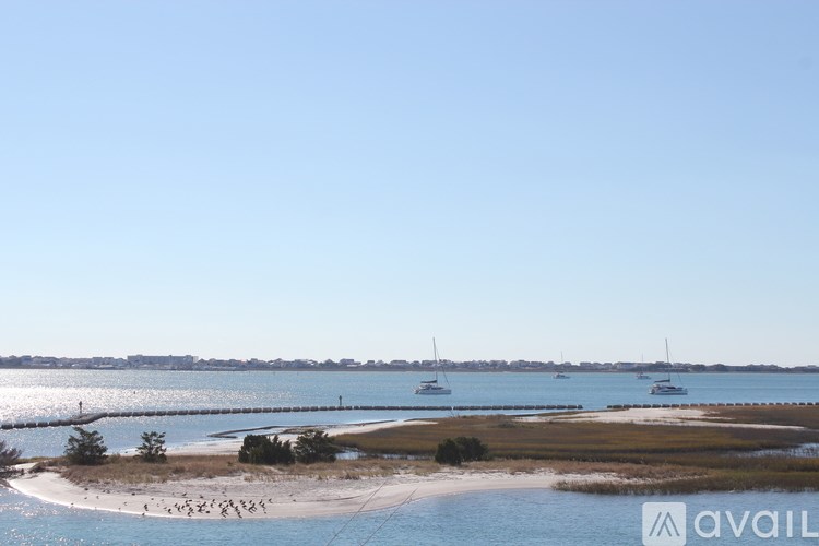 A beach with a few boats in the water and a clear blue sky.