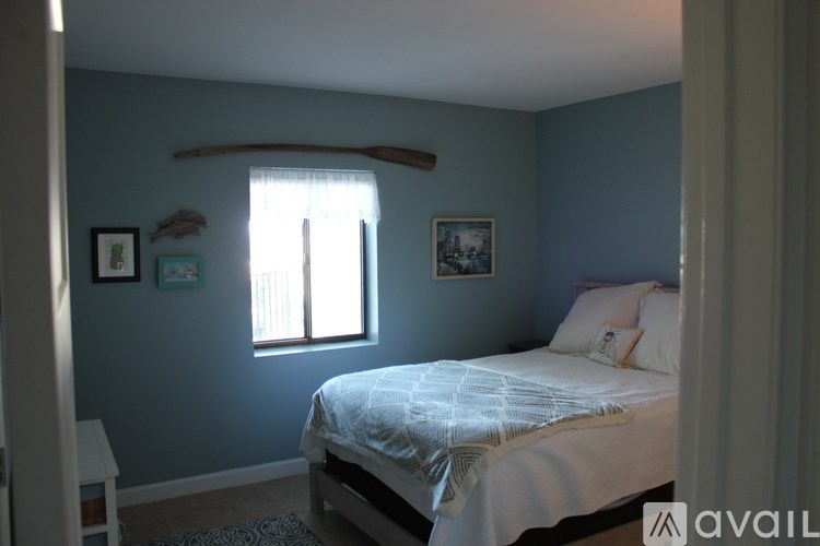 A bedroom with a bed, a window, and pictures on the wall.