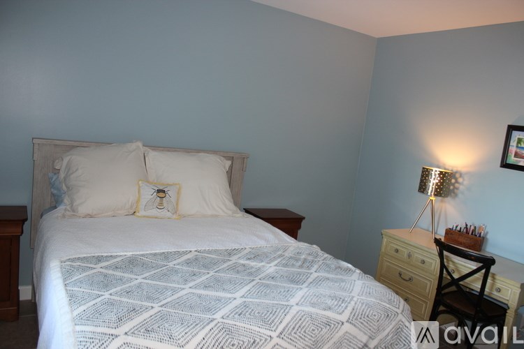 A bedroom with a bed, nightstand, and lamp.