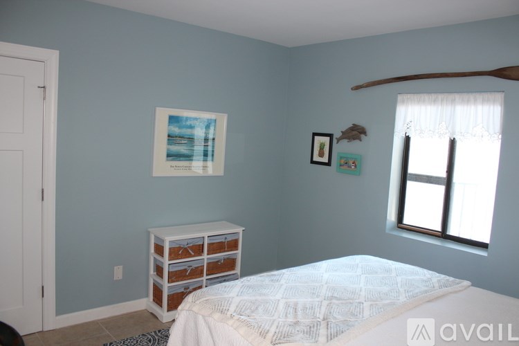 A bedroom with a bed, a dresser, and a painting on the wall.