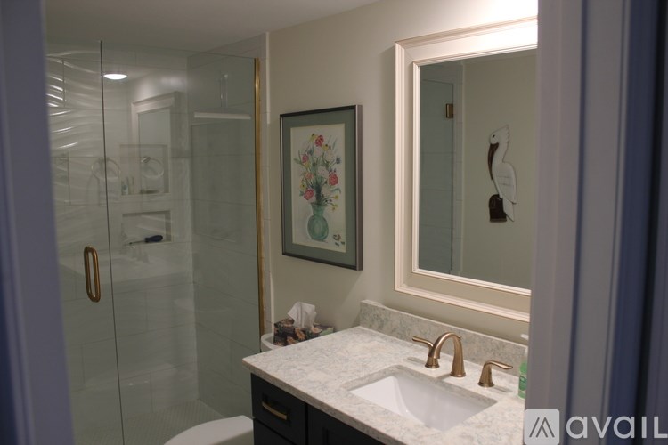 A bathroom with a sink, mirror, and shower.