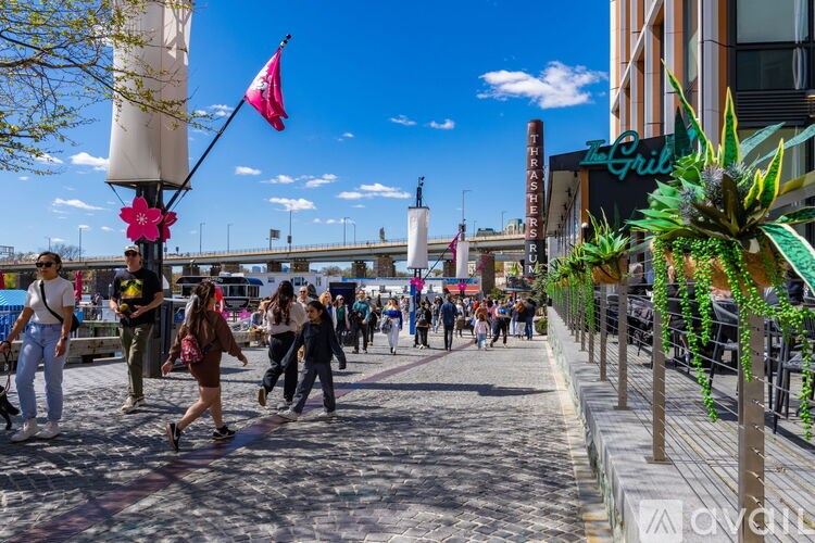 People walking on a sidewalk with a bridge in the background.