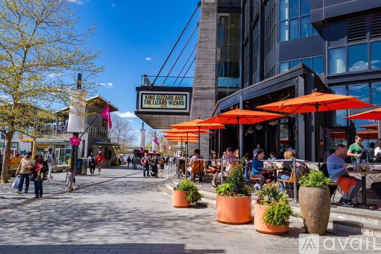 A busy street scene with people walking and sitting at outdoor tables.