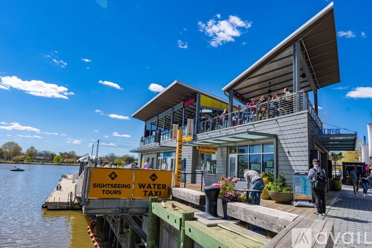 A water taxi dock with people on the dock and a building in the background.
