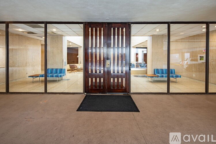 A hallway with a black mat in front of a glass door with a wooden frame.