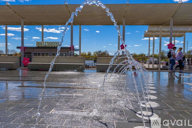 A water fountain in the middle of a plaza with a building in the background.