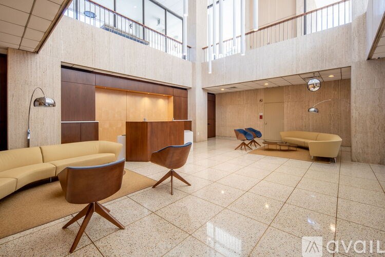 A spacious living room with a yellow sofa, wooden chairs, and a white bathtub.