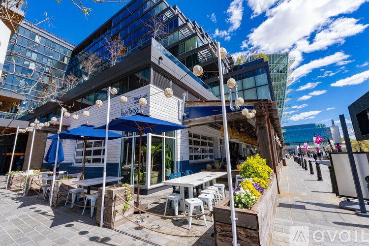 A modern outdoor dining area with tables and chairs under umbrellas.