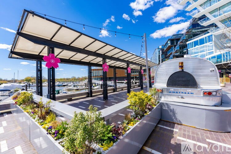 A white airplane is parked under a canopy on a sunny day.