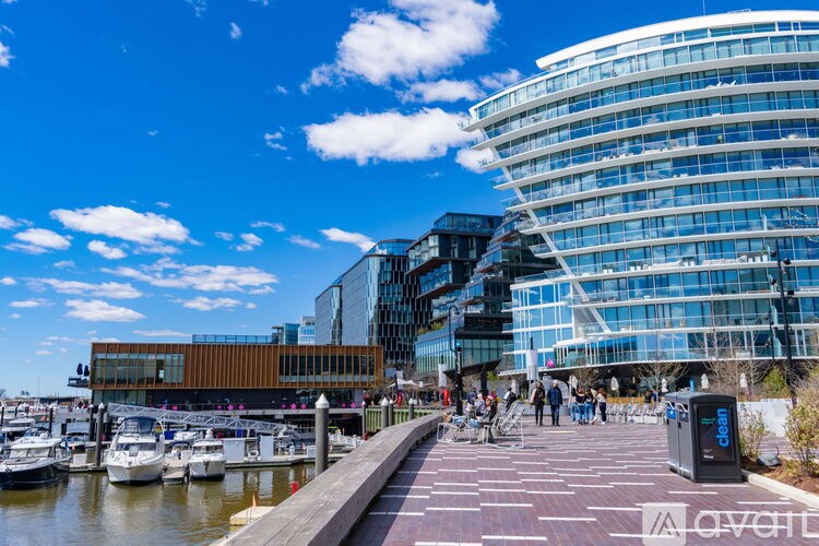 A modern glass building with a curved design sits next to a marina with several boats docked.