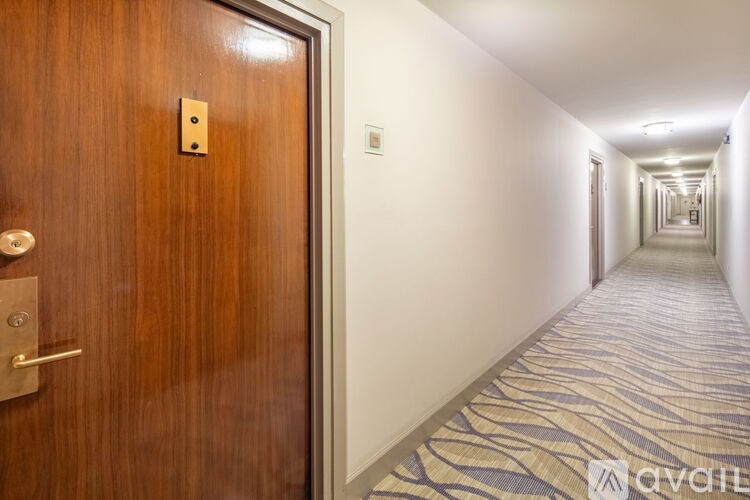A hallway with a wooden door on the left and a carpeted floor.