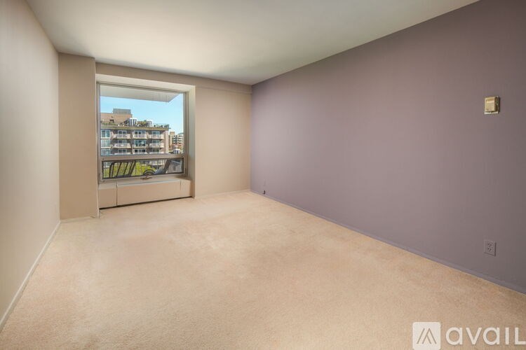 A room with a window overlooking a building with a balcony.