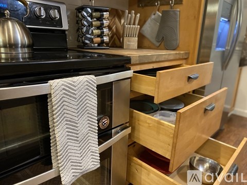 A kitchen with a black stove top and wooden drawers.