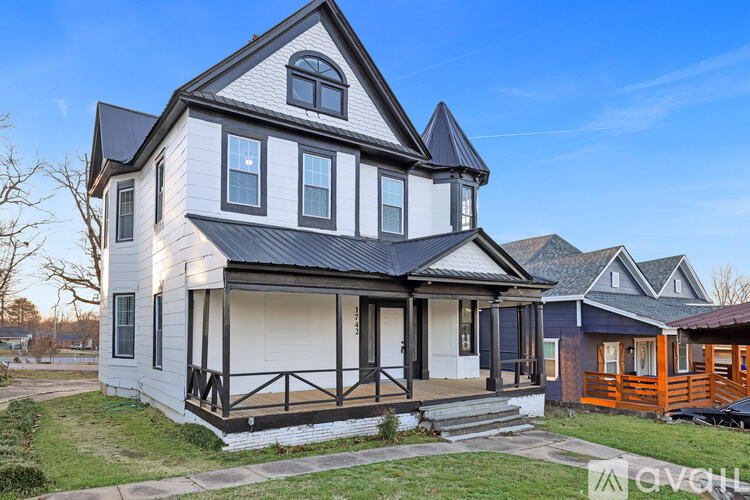 A white house with a black roof and a porch.