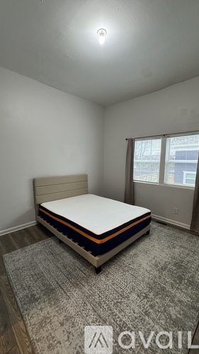 A bedroom with a bed, carpet, and a window.