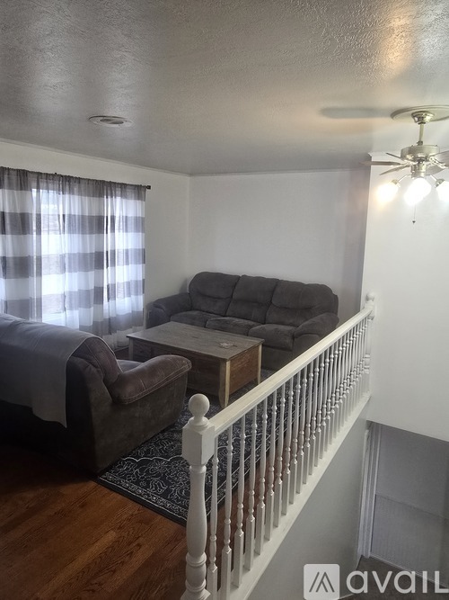 A living room with a couch, chair, and a window with curtains.