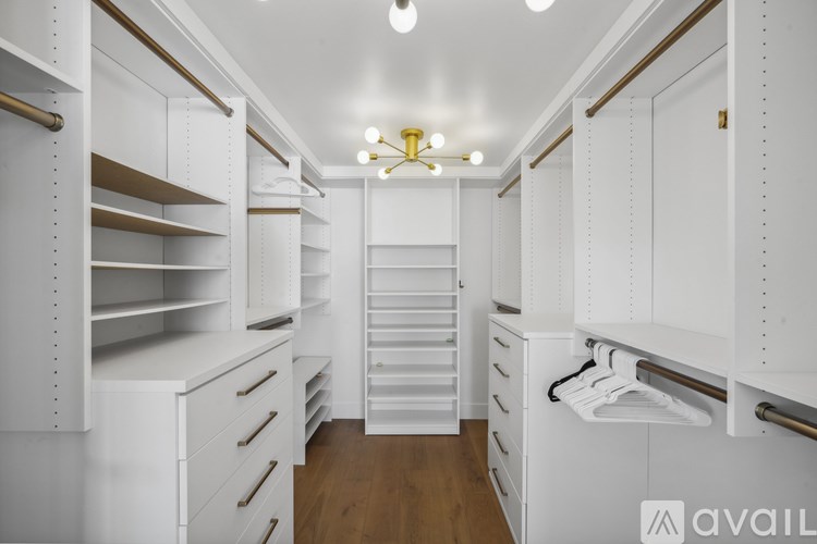 A spacious walk-in closet with white shelving and drawers.