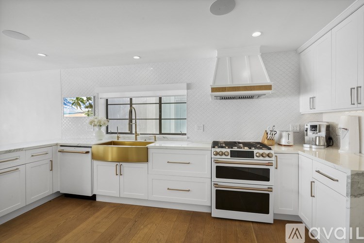 A modern kitchen with white cabinets and a wooden floor.