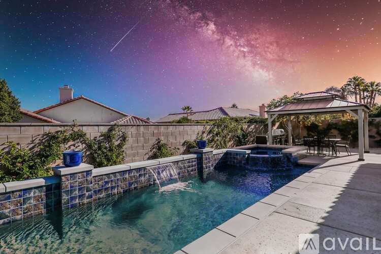 A swimming pool with a view of the night sky and a house in the background.