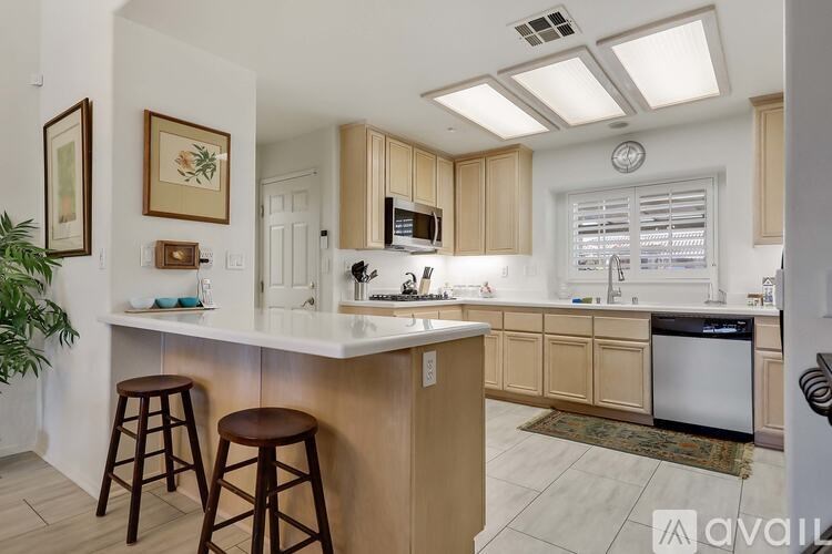 A kitchen with a white countertop and wooden cabinets.