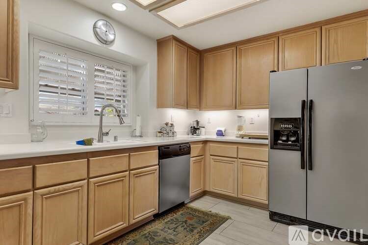 A kitchen with wooden cabinets and a stainless steel refrigerator.
