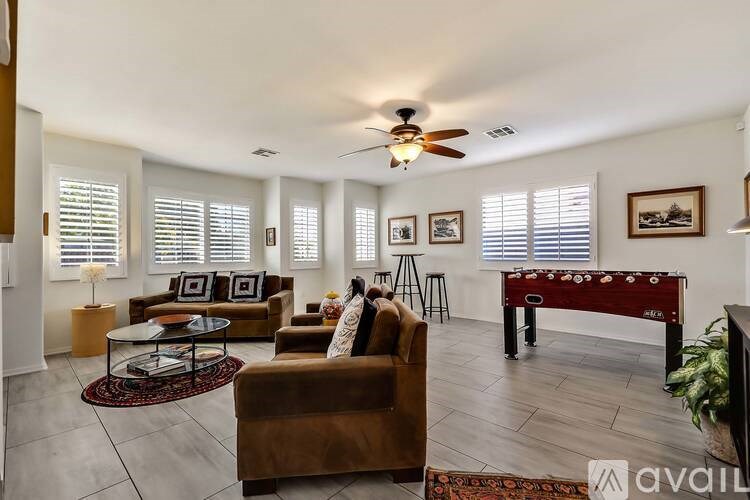 A living room with a brown couch, a red table, and a ceiling fan.