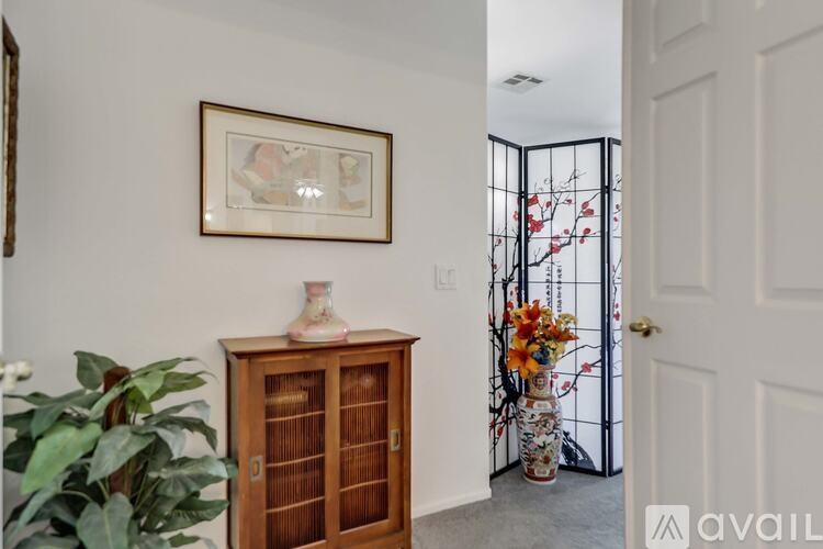 A room with a wooden cabinet, a framed picture on the wall, and a door with a gate.
