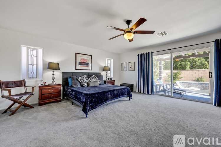 A bedroom with a bed, chair, and ceiling fan.
