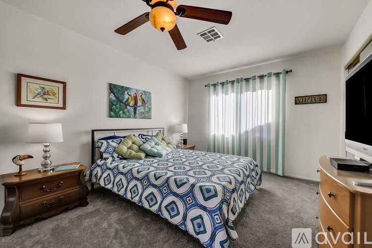 A bedroom with a bed, nightstand, and a ceiling fan.