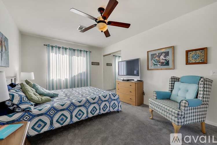 A bedroom with a bed, chair, and television.