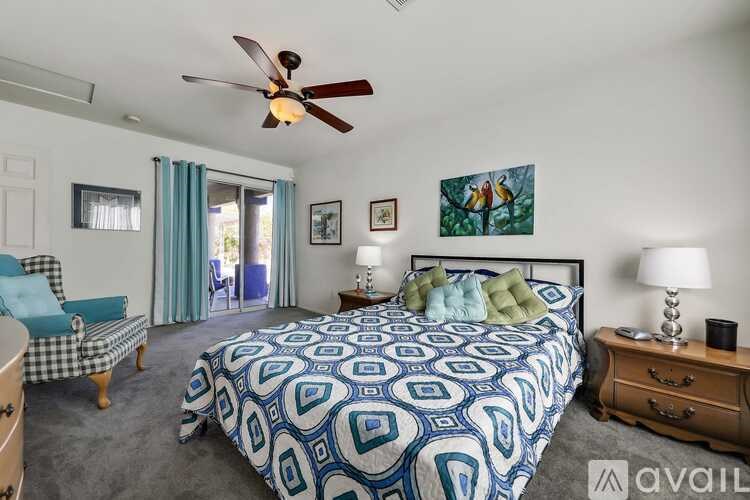 A bedroom with a patterned bedspread and a ceiling fan.