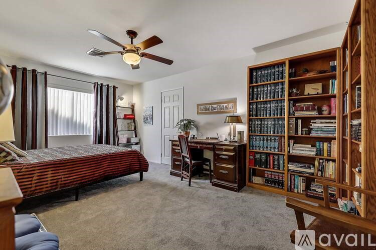 A bedroom with a bed, desk, and bookshelf.