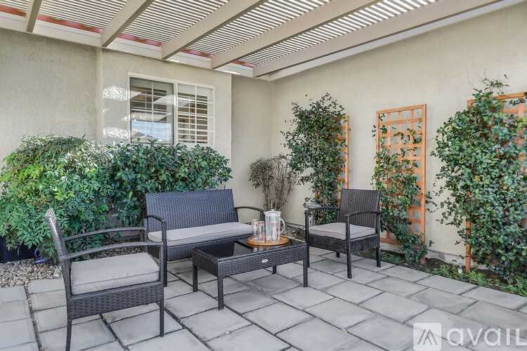 A patio with a table and chairs and plants.