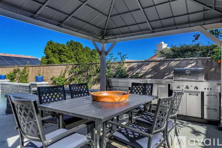A table with chairs and a bowl on it is set up under a canopy.