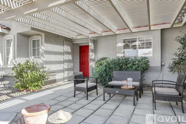 A patio with a table, chairs, and a red door.